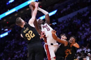 MIAMI, FLORIDA - APRIL 26: Bam Adebayo #13 of the Miami Heat collects a rebound against Dean Wade #32 of the Cleveland Cavaliers during the fourth quarter in Game Three of the Eastern Conference First Round NBA Playoffs at Kaseya Center on April 26, 2025 in Miami, Florida.